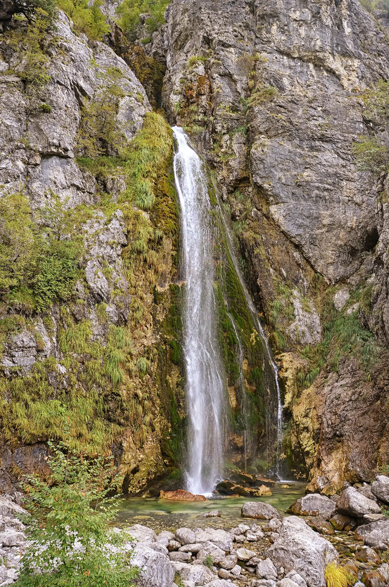 Grunas Waterfall pouring down a mossy cliff in Theth National Park